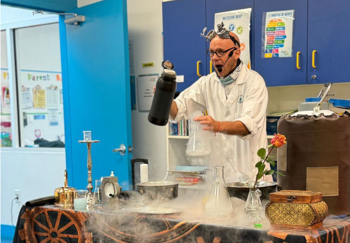 A teacher in a lab coat performing a chemistry experiment with dry ice creating fog and bubbles for preschool students