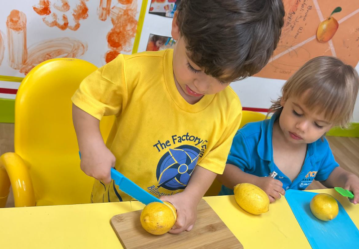 Two young students at Pines West Academy using plastic knives to slice lemons during a hands on kitchen activity